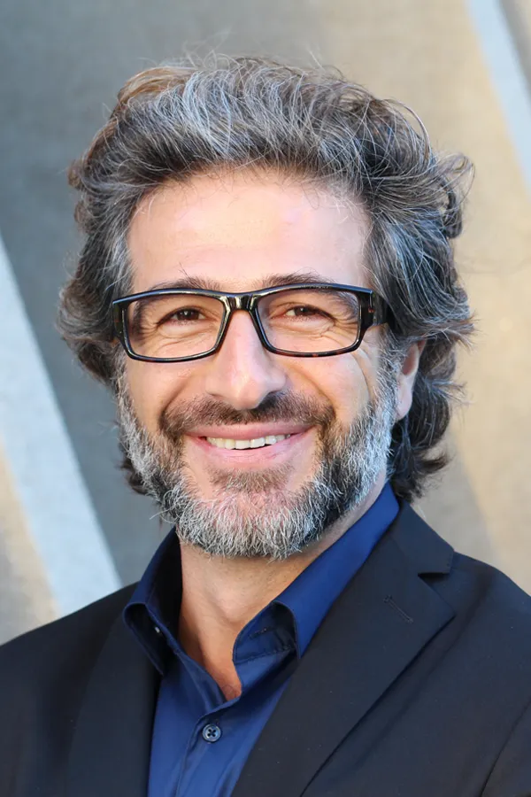 A man with glasses, salt and pepper hair and a beard smiling because he received treatment for andropause and low testosterone from Dr. Bahar Amin in North York.