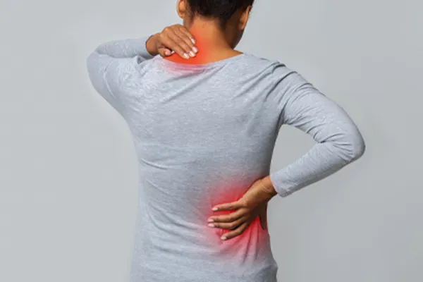 An image from behind of a woman suffering from Fibromyalgia holding her hands on her neck and lower back. Get fibromyalgia care from Dr. Bahar Amin in North York.