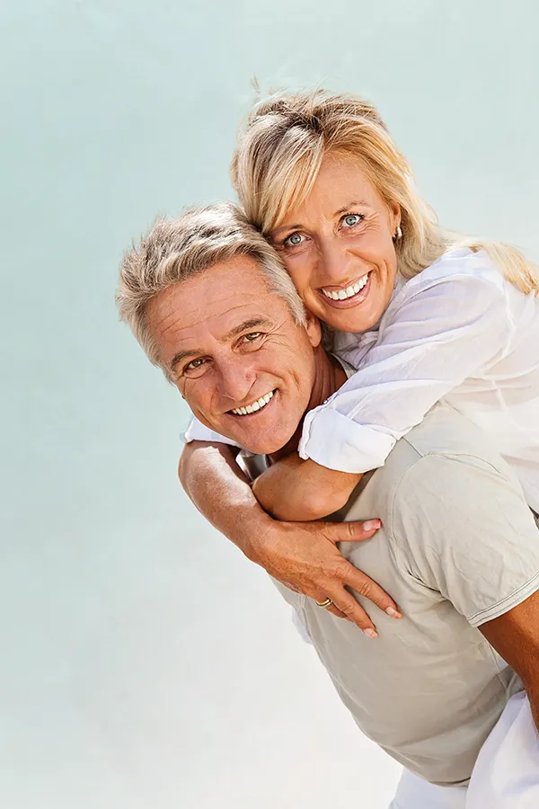 A happy mature couple having fun - the husband is carrying his wife on his back. Get treatment for food allergies from Dr. Bahar Amin in North York.