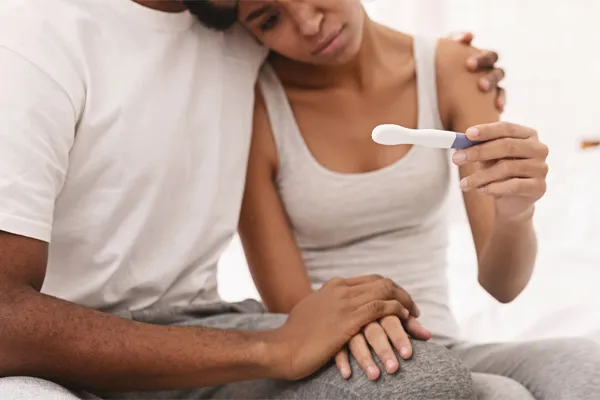 A couple look at a pregnancy test with disappointment. Get male infertility treatment from Dr. Bahar Amin in North York.