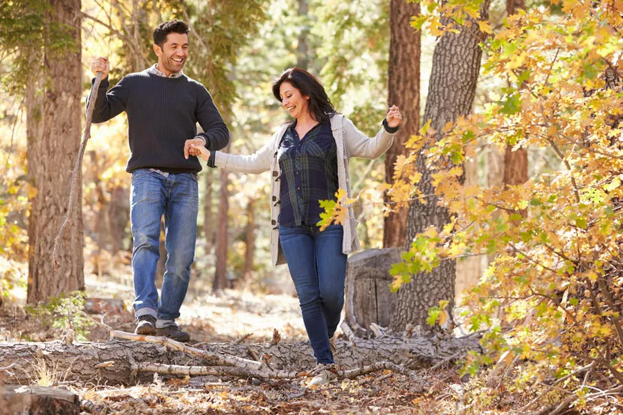 A couple happily hiking in the forest in fall. Get treatment for Lyme Disease from Dr. Bahar Amin in North York.
