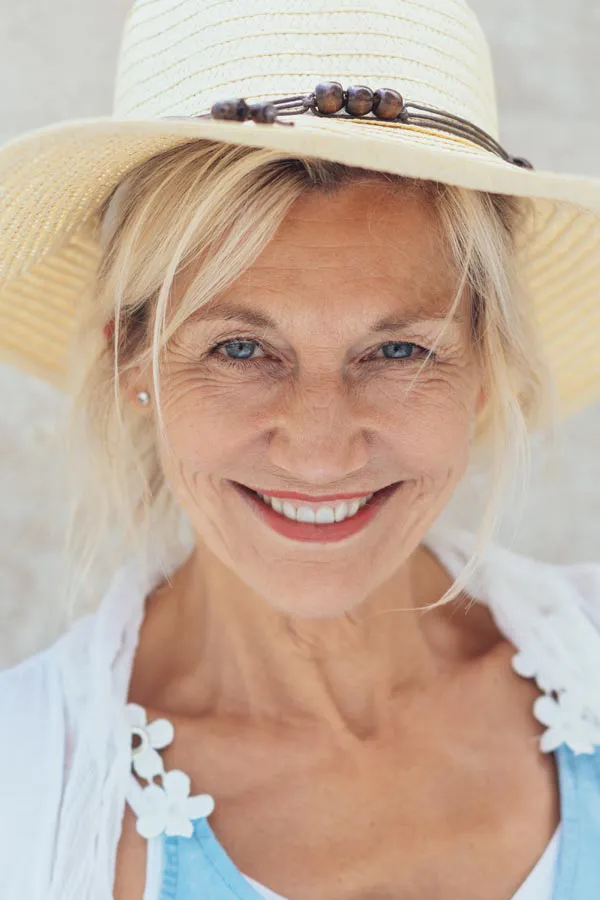 A beautiful, smiling older woman with blonde hair and a sunhat, happy with menopause treatment from Dr. Bahar Amin in North York.