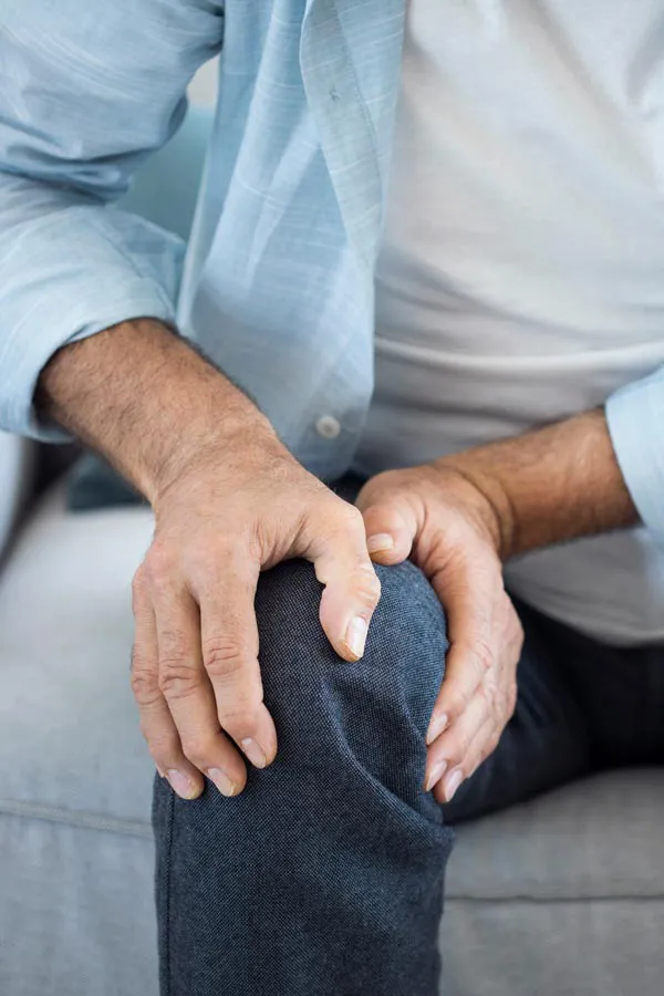 A close-up of a man holding his knee while experiencing pain from osteoporosis. Get osteoporosis treatment from Dr. Bahar Amin in North York.