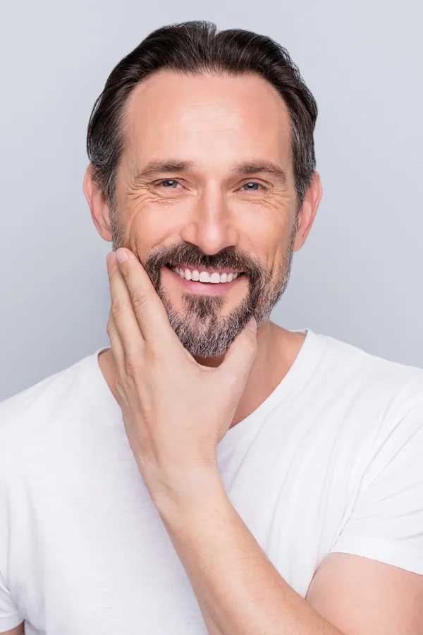 Middle-aged man touching his cheek and smiling confidently after finding relief with functional medicine for sjogren's syndrome offered by Dr. Bahar Amin in North York.