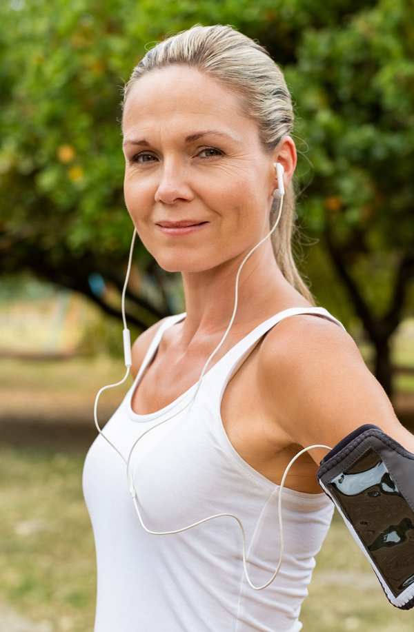 Middle-aged, active woman taking a break to smile at the camera during a run, representing successful Bioidentical Hormones for Fibromyalgia Relief offered by Dr. Bahar Amin in North York.