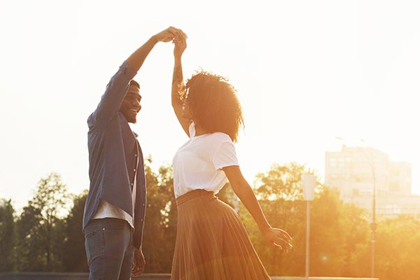 Couple dancing in the sunset with a city skyline view in the background. Schedule your consultation for the six-month precision health program offered by Dr. Bahar Amin in North York.