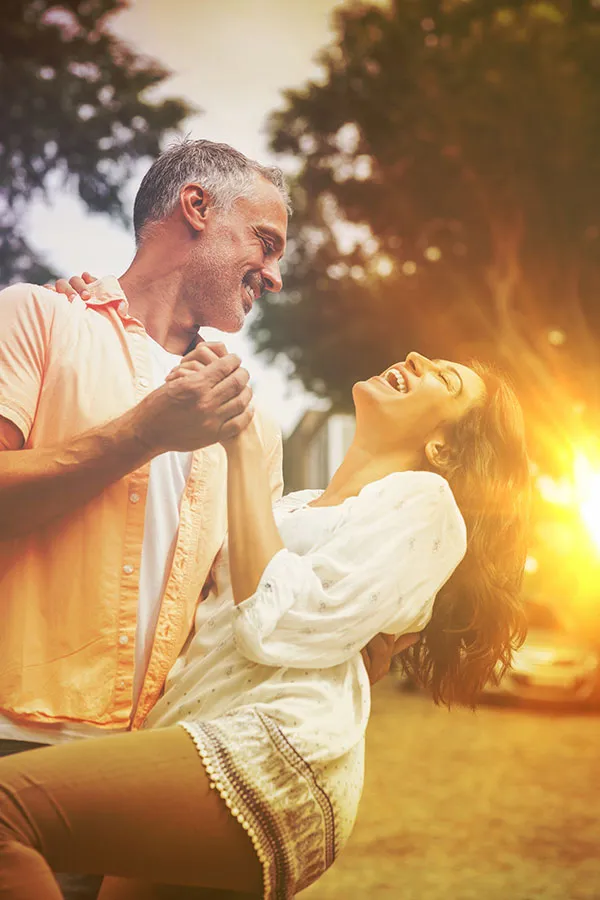 Happy middle-aged couple laughing and dancing together outside at sunset. Receive personalized, concierge care through Dr. Bahar Amin's six-month precision health program in North York.